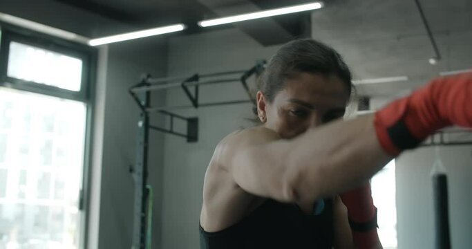 Mixed martial art fighter woman does shadow boxing to the camera in the fight club, female fighter is fighting with shadow, kickboxer training strikes in gym, 4k 120fps Prores HQ