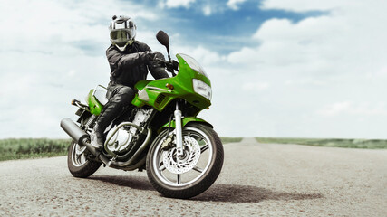 A man on a green motorcycle turns in front of the camera