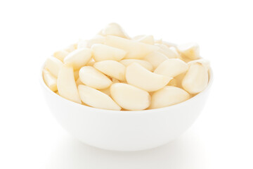 Close-Up of organic fresh peeled garlic (Allium sativum) in white ceramic bowl over white background