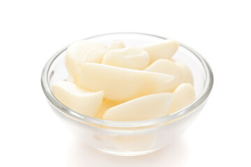 Close-Up of organic fresh peeled garlic (Allium sativum) in transparent glass small bowl over white background