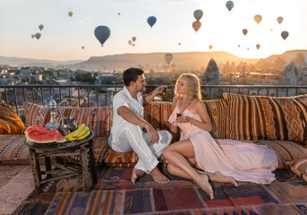 A couple and their romantic breakfast in Cappadocia on the amazing background of hundred flying...