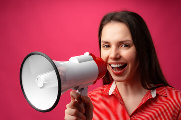 Young brunette woman shouting in megaphone against pink background