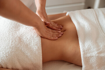 Obraz na płótnie Canvas Masseuse massaging female client abdomen in spa salon