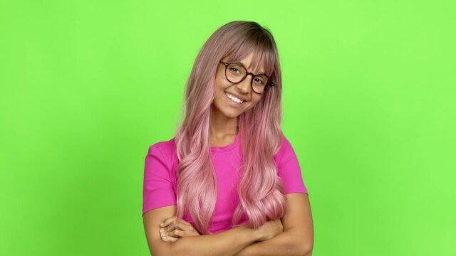 Young woman with pink hair with glasses smiling over isolated background. On green screen chroma key