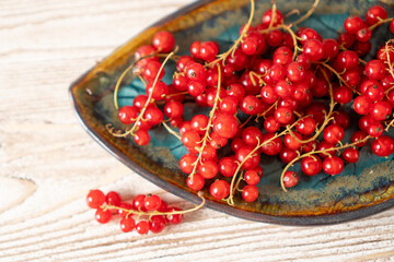 Top view of red currant on beautifull plate on wooden table. Bunch of fresh red currants on a plate