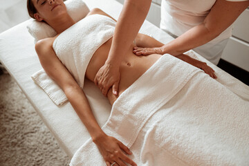 Masseuse hands massaging woman abdomen in spa salon