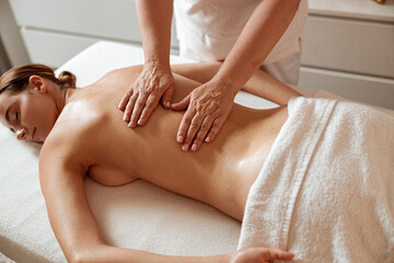 Obraz na płótnie Canvas Charming woman receiving professional massage in spa salon