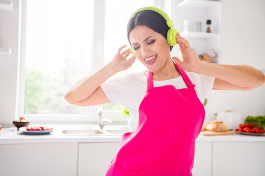Photo of shiny funny young lady wear pink apron cooking dinner enjoying music headphones smiling indoors room home house
