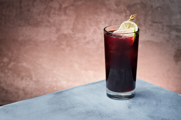 Red berry lemonade with ice in beautiful glass on textured background. Space for text. High quality photo