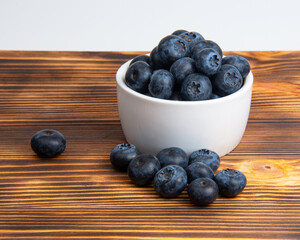 Fresh blueberry in white dish on wooden background