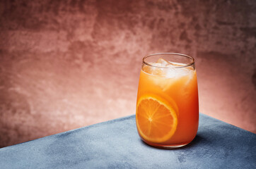 Orange lemonade, orange fresh with ice in beautiful glass on textured background. Space for text. High quality photo
