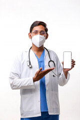 Young indian doctor showing smartphone screen over white backgro