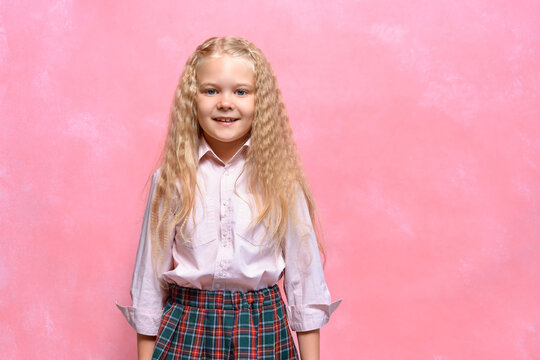 Portrait Of Cute Little Schoolgirl Girl In Shirt And Skirt. Pink Background. Copy Space