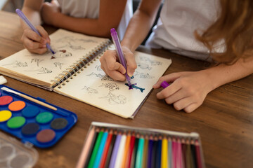 girls drawing at table with colorful pencils, spending time together