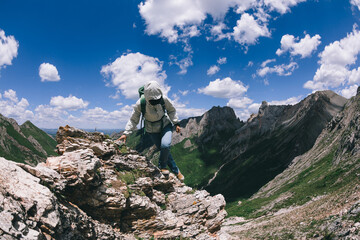 Successful woman backpacker hiking on alpine mountain top