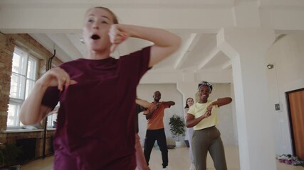 Zoom in shot of group of young multiethnic men and women dancing with female teacher and then taking break during dance class in studio