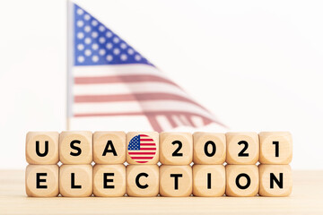USA 2021 election concept. Wooden block with text and american flag at background. Copy space