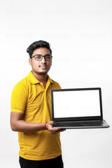 Young indian man showing laptop screen over white background.