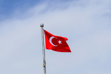 National flag of Turkey against a blue sky with white clouds