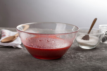 grated strawberries with sugar in a transparent bowl while making strawberry jam