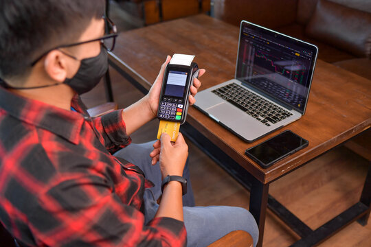 Man sitting at a table making a contactless payment on a credit card reader