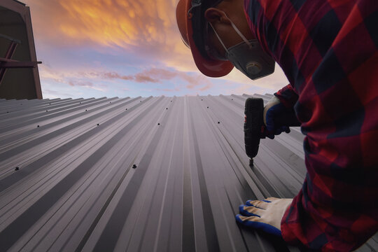Construction worker installing metal sheets on a roof, Thailand