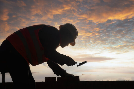 Close-up Silhouette of a Bricklayer building a wall on a construction site, Thailand