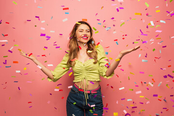 smiling woman with outstretched hands near confetti on pink