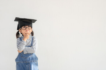 Happy Asian school kid graduate thinking with graduation cap