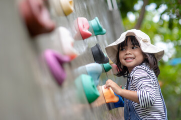 Asian little girl climbing a rock wall © FAMILY STOCK