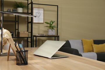 Comfortable workplace with laptop on wooden table in room. Interior design
