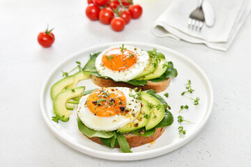Fried eggs, avocado and greens on toasted bread