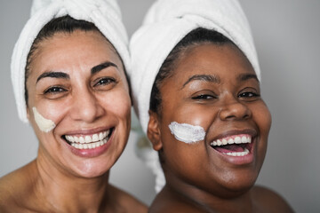 Multiracial senior and young women doing beauty treatment using skin masks - Body care concept -...