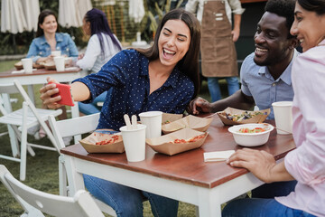 Multiracial people having fun doing selfie with mobile phone at food truck restaurant outdoor - Focus on african american man face