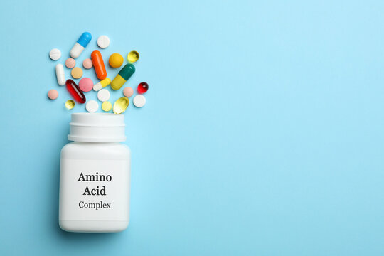Plastic bottle with Amino Acid Complex and pills on light blue background, flat lay. Space for text