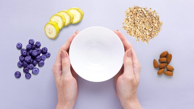 Creative food diet health concept footage movie stop motion video gif bowl dish with healthy breakfast oatmeal corn flackes fruits berries blueberry banana  yoghurt on grey background.