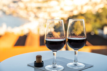 Tasting of different fortified dessert ruby, tawny port wines in glasses with view on Douro river, porto lodges of Vila Nova de Gaia and city of Porto, Portugal