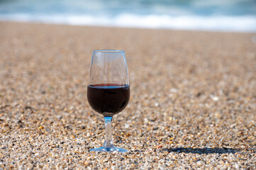 Tasting of different fortified dessert ruby, tawny port wines in glasses on sandy beach with view on waves of Atlantic ocean near Vila Nova de Gaia and city of Porto, Portugal