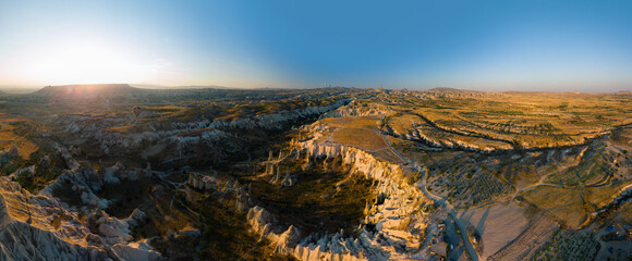 Fototapeta premium Aerial wide view of Love Valley Peri Bacalari Sunset over Red valley in Cappadocia canyon, mountains and balloons.. Nevsehir Province. Turkey