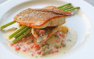 Plate of pan seared sea bass with tomato caper mustard cream sauce