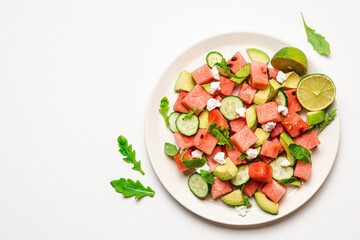Watermelon salad with avocado, cucumber, feta cheese and arugula. Summer fruit salad. Top view, copy space