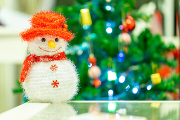 Snowman doll on the defocused of christmas tree background.