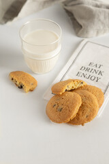 cookies and milk in a glass on a white table with a napkin