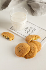 cookies and milk in a glass on a white table with a napkin