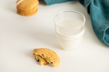 cookies and milk in a glass on a white table with a napkin