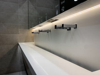 Close up view of modern white sink and abstract metal faucet in public toilet.