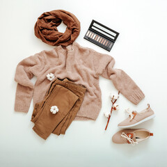 Fashion basic female clothes shoes set beige brown colors knitted sweater scarf and cotton flowers cosmetics. Flat lay Spring winter woman female outfit. clothes on white background square.