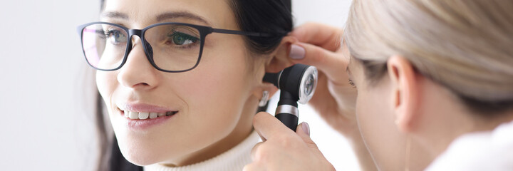 Doctor conducts examinations of ear area for woman