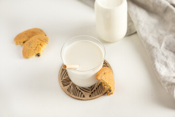 cookies and milk in a glass and bottle  on a white table with a napkin