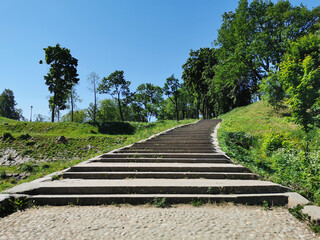 A view from below of a wide stone staircase in the Summer Garden of the city of Kronstadt against the background of a cloudless sky